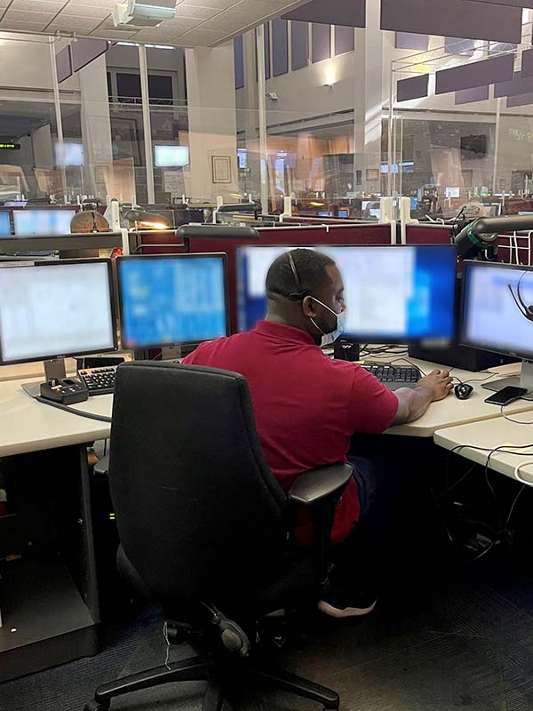 Male dispatcher working on computer with mask on