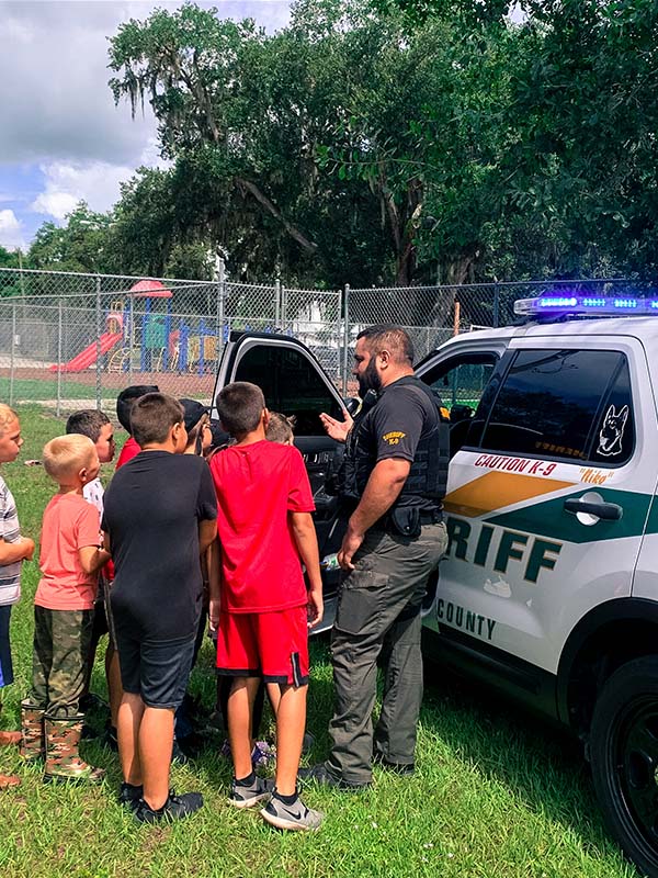 Officer talking with kids next to Squad SUV