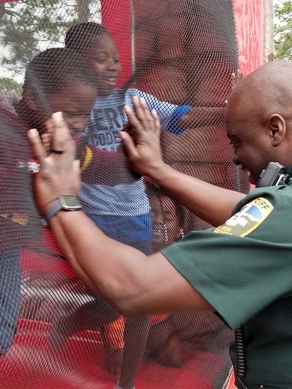 Officer playing with kids that are in a bouncy house